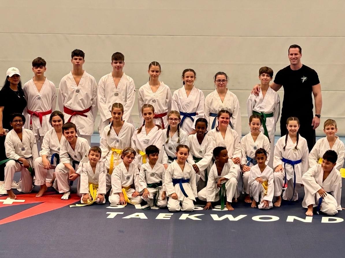 The full Twist Taekwondo squad — students of all ages in their doboks with coaches, posed together on the dojang mat